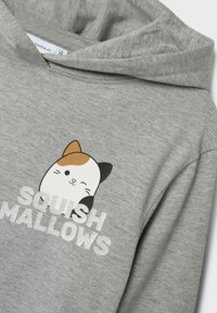 Siva dukserica s grafikom slatke mačke s kaliko uzorkom i natpisom "SQUISH MALLOWS" u debelim, sjajnim slovima. Meko tekstura tkanine.