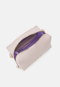 Borsa testurizzata rosa chiaro con chiusura a zip, hardware dorato e un interno viola vivace. Include uno slot per carte e un pannello superiore con logo.