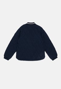 Marinefarget quiltet jakke med rund hals, hvite stripe-detaljer på kragen og mansjettene, samt elastisk kant og mansjetter.