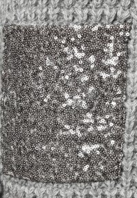 Tessuto a maglia grigio con una grande toppa di paillettes argentee. Le paillettes sono disposte densamente, creando una superficie testurizzata e riflettente.