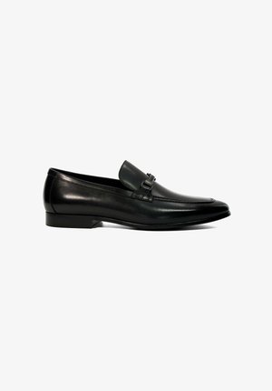 Black leather loafer with a low profile, featuring a decorative buckle detail, subtle stitching, and a smooth finish. Flat rubber sole.