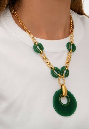 Collier en résine verte avec quincaillerie en ton doré, présentant des maillons circulaires et un grand pendentif circulaire. Des détails texturés rehaussent l'intérêt visuel.