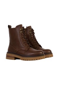 Bruine leren enkelboots met een ronde neus, vetersluiting aan de voorkant en een rubberen profielzool. Heeft gouden oogjes en een lus aan de achterkant.