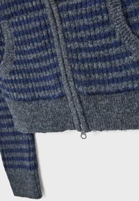 Gestrickter Pullover in Grau und Marineblau mit horizontalen Streifen, ausgestattet mit einem frontalen Reißverschluss und zwei Seitentaschen, strukturierter Stoff.