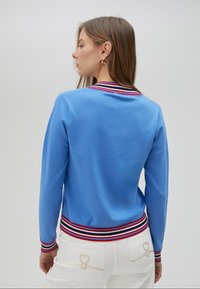 Blåstickad tröja med randig ribbad krage i röd, vit och blå, med slim fit och en texturerad yta.