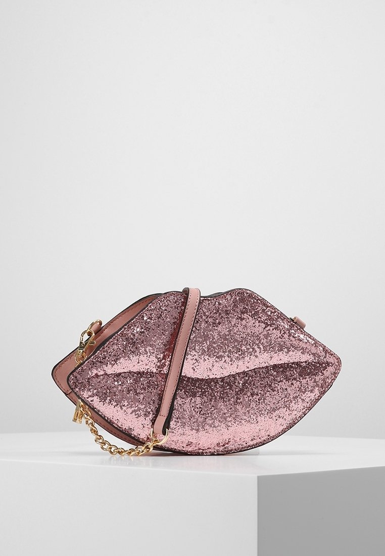 Vaaleanpunainen glitter-kosketus, joka on muotoiltu huuliksi, jossa on sileä nahkaremmi ja kultaketju. Varustettu vetoketjulla.