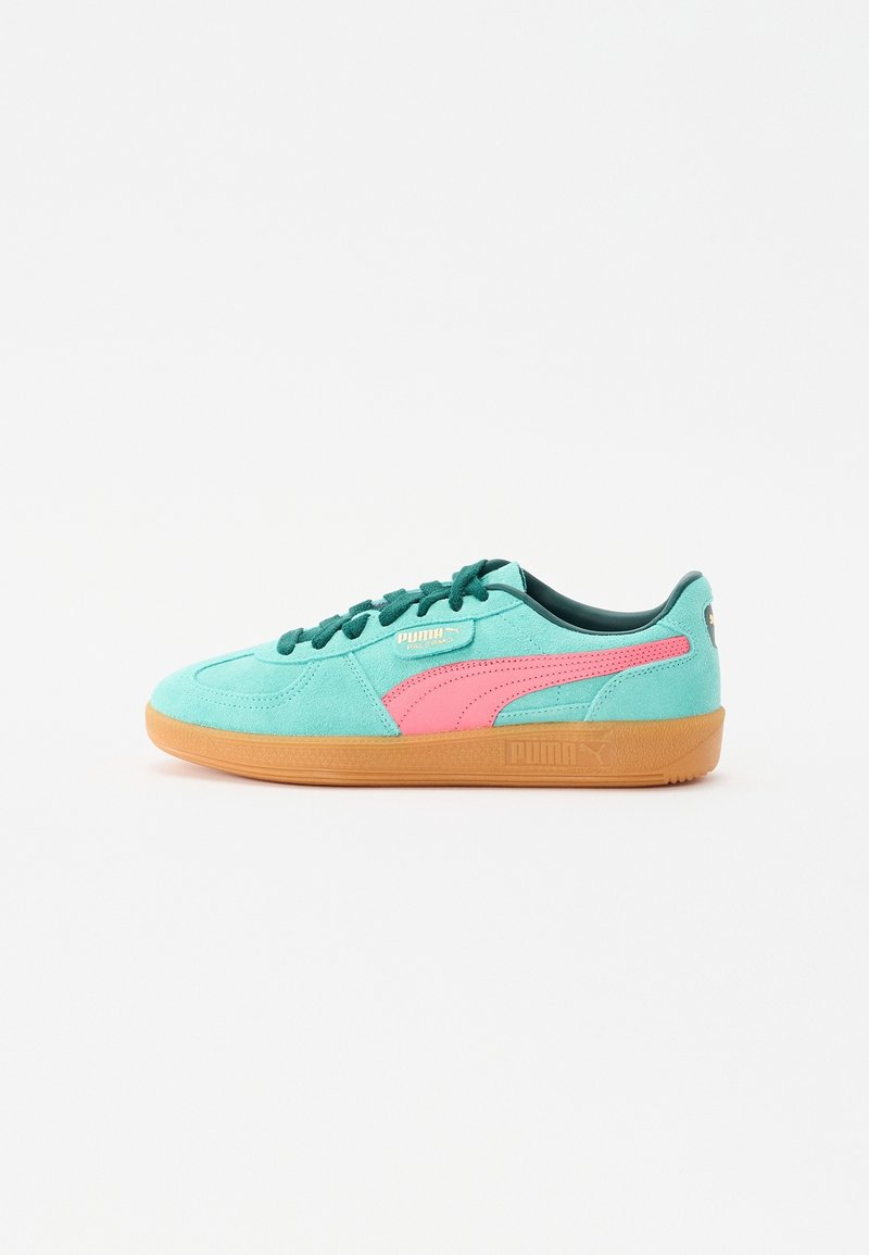 Baskets Puma en daim turquoise avec une bande rose, des lacets vert foncé et une semelle en gomme, vues de profil sur fond blanc.