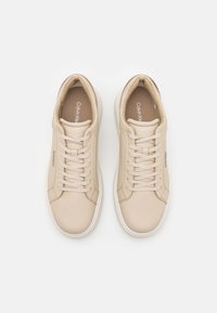 Baskets en cuir beige avec bout rond, lacets plats et semelles intérieures rembourrées. Comprend un branding subtil sur les côtés et des semelles en caoutchouc blanc.