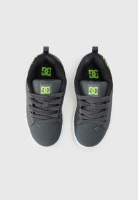 Šedé tenisky s hladkým povrchem, kontrastními zelenými akcenty a bílou gumovou podešví. Vybavení zahrnuje tkaničky a logo na jazyku.