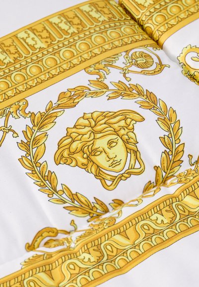 Tissu en soie avec des motifs complexes en or et jaune, présentant une tête de Méduse centrale entourée de feuilles de laurier et de bordures décoratives.