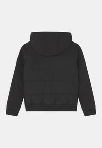 Czarna kurtka z kapturem w stylu puchowym. Posiada gładki górny i pikowany dolny panel. Ściągacze na mankietach i dole. Brak widocznych logo i kieszeni.