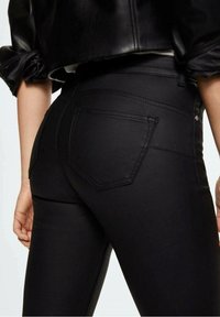 Zwarte denim skinny jeans met een fitted ontwerp, voorzien van een hoge tailleband, achterzakken en zichtbare stiksels.