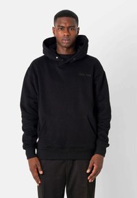 Schwarzer Kapuzenpullover aus weichem Stoff, mit einer Fronttasche, gerippten Bündchen und einem dezenten geprägten Logo auf der Brust.