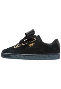 Baskets en daim noir Puma avec semelle noire épaisse, œillets dorés, larges lacets ruban noirs et logo Puma Suede doré sur le côté.