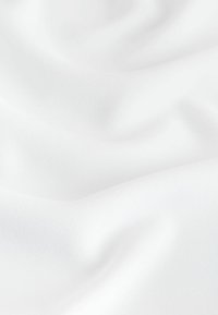 Tissu blanc doux avec de légers plis et une texture subtile sous une lumière diffuse.