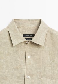 Linen shirt in light beige with a classic collar, featuring a pocket and white buttons. Tags indicate "Massimo Dutti, 100% linen, made in China."