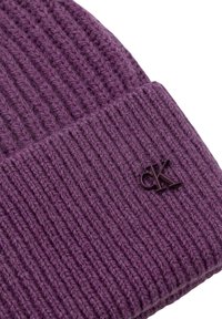 Cappello a maglia viola con texture a coste, caratterizzato da un piccolo logo scuro. Materiale morbido e caldo con design aderente.
