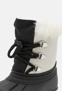 Botas de invierno impermeables en negro y gris, con un ribete de pelo sintético, parte superior de tejido texturizado, cierre de cordones y suela de goma.