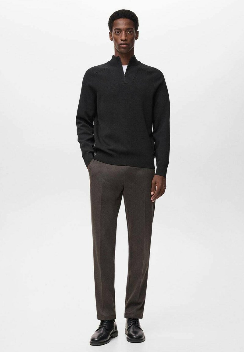 Zwarte gebreide pullover met een hoge kraag, gecombineerd met op maat gemaakte donkerbruine broek en zwarte leren schoenen. Soepele textuur, aansluitende pasvorm.