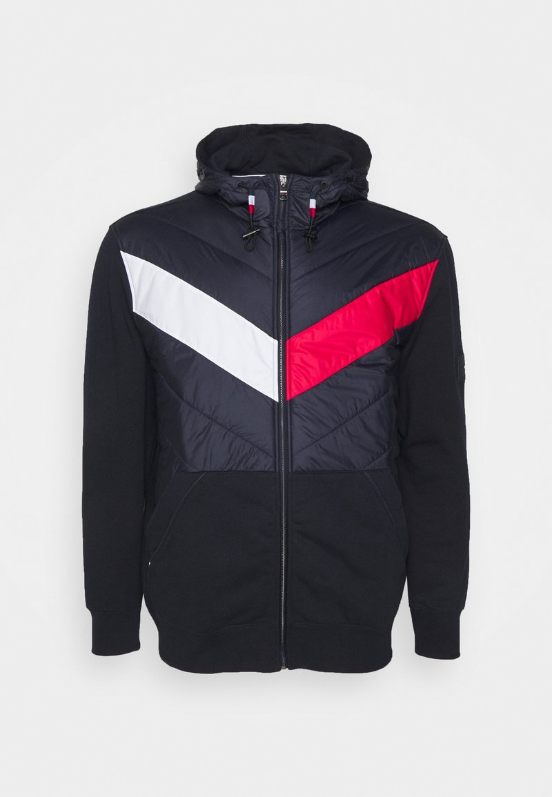 Hættezip-sweatshirt med navy, hvid og rød chevronmønster, blød stoftekstur og frontlommer med justerbare snore.