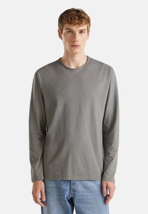 Langarmshirt van gedimd grijs katoen met een ronde halslijn, met een smooth textuur en een relaxte pasvorm. Gecombineerd met lichtblauwe jeans.