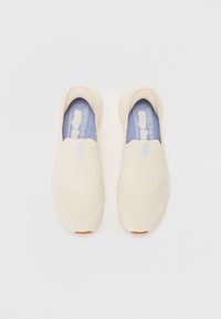 Béžové slip-on tenisky s texturovaným svrškem, elastickým pásem, modrou stélkou a gumovou podrážkou. Jednoduchý design se sotva znatelnými rýhami.