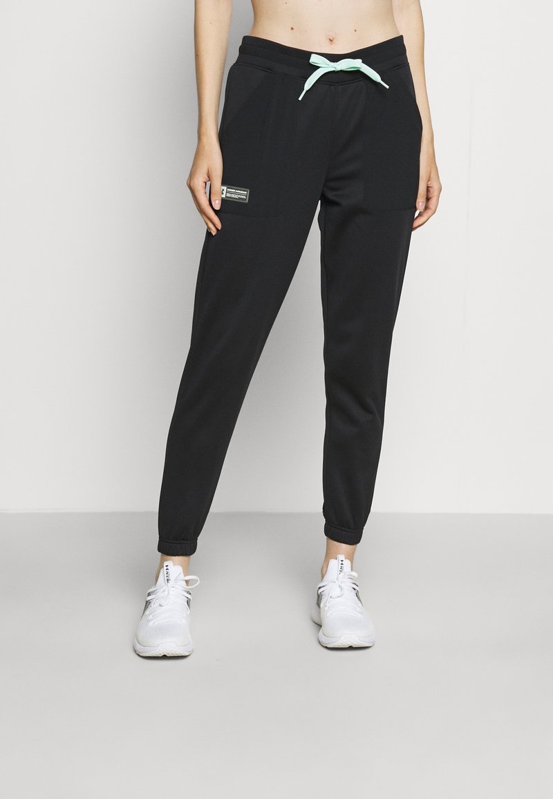 Pantalones deportivos negros de material suave con un cordón verde menta, bolsillos laterales, puños elásticos y una pequeña etiqueta en la parte delantera.