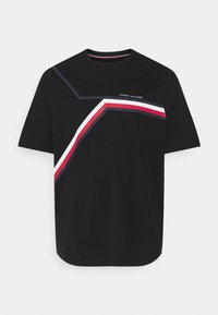 Sort bomulds T-shirt med korte ærmer, der har et geometrisk design i hvid, rød og blå. "TOMMY HILFIGER" logoet trykt over grafikken.