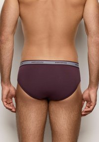 Slip scuro viola con cintura elastica grigia che porta il nome del marchio "yamamay". Il tessuto appare lucido e aderente.