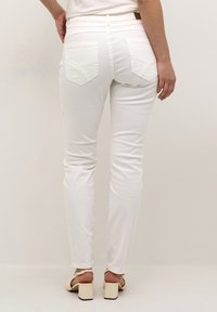 Slim-fit valged denim teksad kõrge vöökohaga, millel on kaks tagumist taskut dekoratiivõmblustega ja kitsas ääreline.