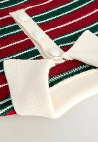 Rood en groen gestreepte gebreide stof met witte knopen en een crèmekleurige kraag. Beschikt over een zachte textuur en een casual ontwerp.