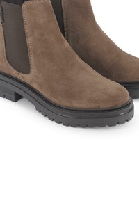 Botines de ante marrón con paneles laterales elásticos, suela de goma negra resistente y banda de rodadura texturizada para mejorar la tracción.