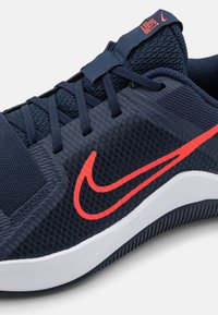 Shoe urheilujalkine navy-tunnelilla, jossa on punainen Nike-logomerkki, teksturoitu päällinen, nauhoitusjärjestelmä ja valkoinen kumipohja, jossa on vaakasuoria uria.