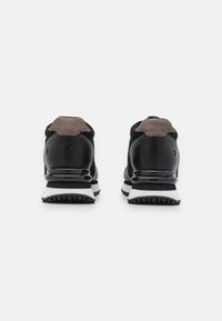 Scarpe sportive nere con una parte superiore testurizzata, dettagli in suede e una suola bianca e nera. Presentano un tallone imbottito e una suola in gomma.