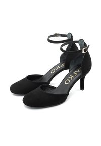 Zwarte suède damesankelbandjes met puntige neuzen, slanke mid-height stilettohakken en gouden gespafsluitingen op een witte achtergrond.