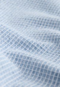 Light blue textured fabric with a grid pattern, featuring a woven design and soft, breathable texture. Suitable for various applications.