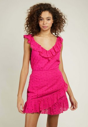 Robe rose avec un col et des manches à volants, présentant des détails en œillets. La jupe a un design à volants superposés, fabriquée en tissu léger.