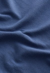 Tengerészkék szövet, sima textúrájú, enyhén gyűrött, puha anyagból készült, egyenletes szövésmintával.