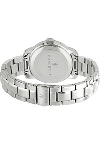 Orologio in acciaio inossidabile argentato con bracciale a maglie e cassa rotonda. Presenta una corona e un logo del marchio inciso sul retro e sulla chiusura.