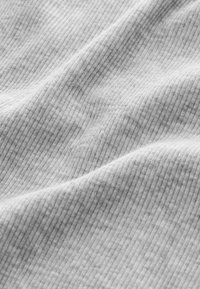 Close-up of soft, light gray ribbed fabric with subtle folds creating a wavy texture and linear pattern across the surface.