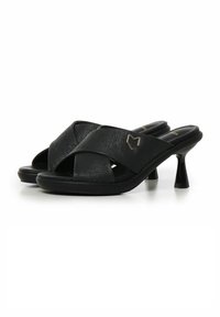 Sandalias de tacón negro con correas cruzadas texturizadas, un tacón cuadrado y detalle en acento dorado. Material suave similar al cuero.