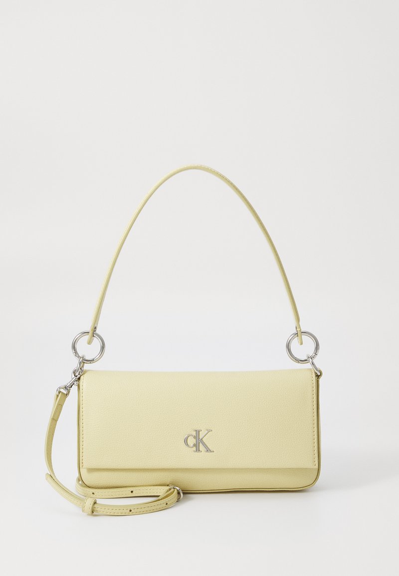 Sac à main en cuir jaune avec une texture lisse, présentant des accessoires en métal argenté, une bandoulière réglable et un accent de logo sur le devant.