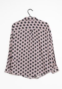 Blouse à manches longues avec un motif d'étoiles rose et noir, fabriquée en tissu léger. Présente un col classique et un empiècement au dos avec un détail de plis.