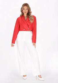 Rød cropped blazer med dobbeltknaplukning, parret med højtaljede hvide vide bukser og hvide spidse hæle.