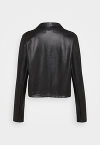 Musta nahkatakki, jossa suora leikkaus, pitkät hihat ja klassinen kaulus. Sileä pinta, minimalistinen muotoilu ilman metalliosia.