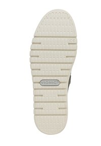 Semelle de chaussure Vionic, en caoutchouc crème texturé avec des rainures de traction visibles et un patch logo central. Bout rond avec des bords contourés.