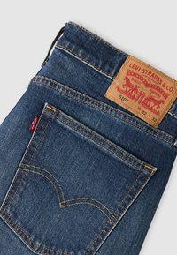 Σκούρα μπλε τζιν από denim με κλασικό σχέδιο. Διαθέτουν δερμάτινο ταμπελάκι στη ζώνη και αντίθετη πορτοκαλί ραφή. Η πίσω τσέπη έχει χαρακτηριστικό σχέδιο.