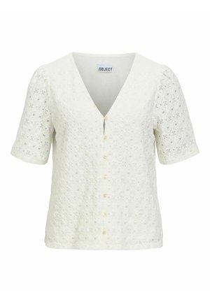 Blouse blanche à manches courtes avec col en V, boutons sur le devant et tissu ajouré floral texturé.