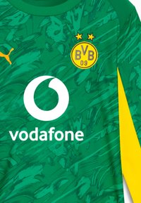 Vihreä ja keltainen jalkapalloselkä, jossa on BVB 09 -logo, Vodafone-sponssi ja Puma-embleemi kuviollisella kankaalla.