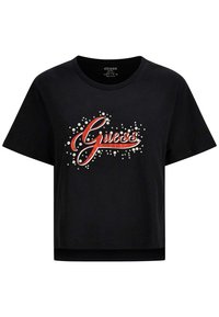 Camiseta corta negra de algodón, con la palabra "Guess" en rojo con decoraciones y acentos blancos alrededor.